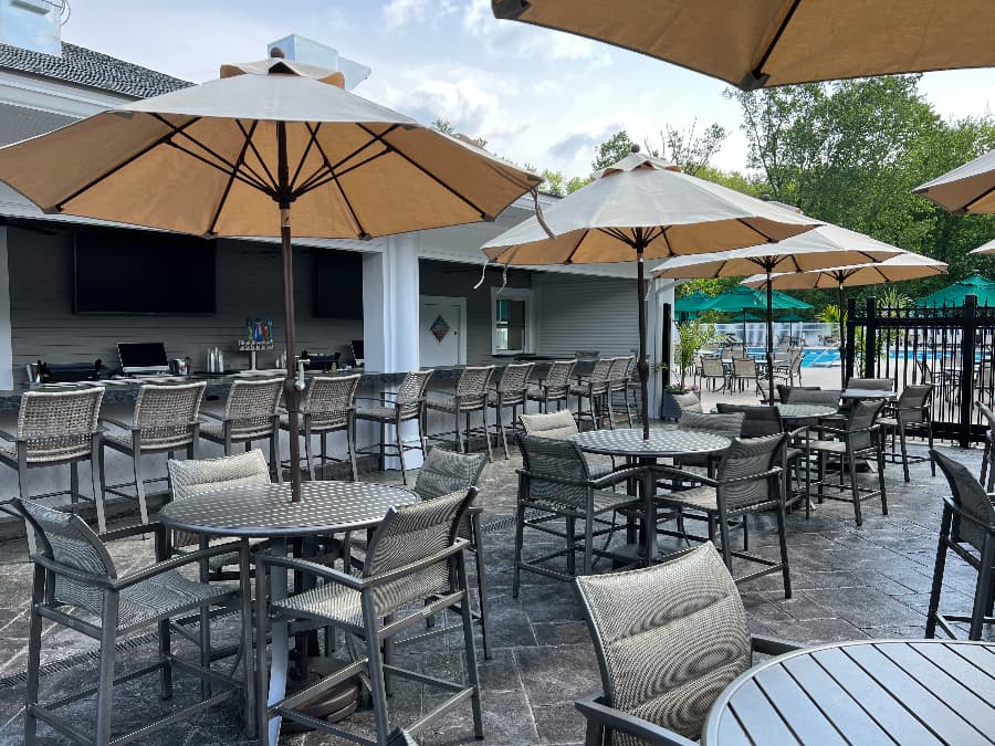 Poolside seating area with tables, umbrellas, and chairs 